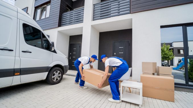 two-removal-company-workers-unloading-boxes-furniture-from-minibus